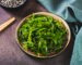 Delicious wakame seaweed salad on a plate and sesame seeds in a bowl on the table