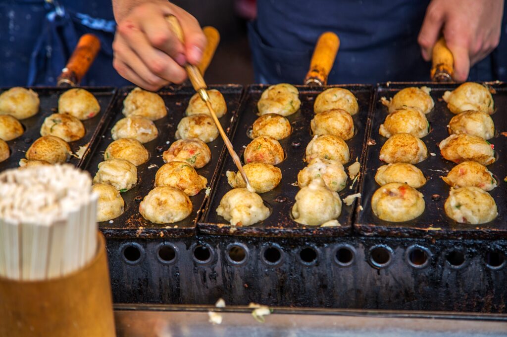 Takoyaki being grilled at a street food stall in Osaka, Japan